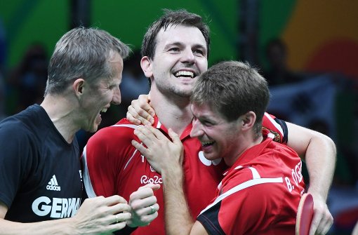 Bastian Steger (rechts) und Timo Boll (Mitte) feiern die Bronze-Medaille mit ihrem Trainer Jörg Rosskopf Foto: dpa
