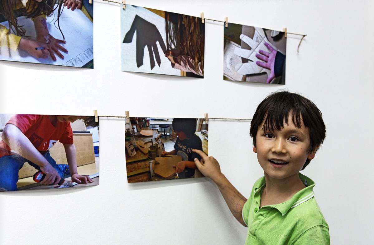 Lukas aus der Kita Brunnenwiesenstraße zeigt stolz Fotos, die seine Arbeit dokumentieren.