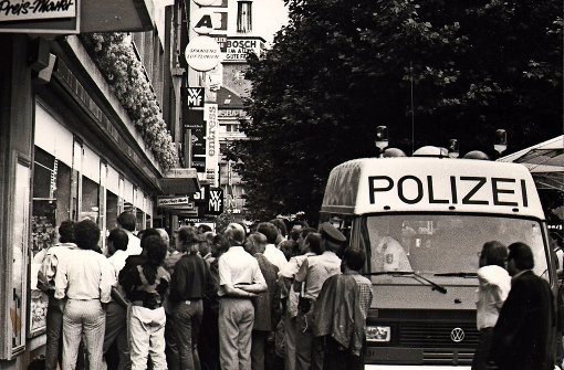 Fußballfans bei der EM 1988 vor einem Schaufenster in der Fußgängerzone der Königstraße –  Polizeibeamte fahren heran und schauen   mit zu. Foto: Thomas Hörner