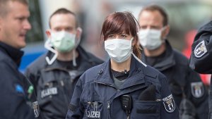 Vor dem Jobcenter in Berlin tragen Polizisten Mundschutz - doch der Ebola-Verdacht hat sich wohl nicht erhärtet. Foto: dpa