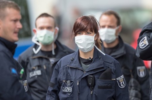 Vor dem Jobcenter in Berlin tragen Polizisten Mundschutz - doch der Ebola-Verdacht hat sich wohl nicht erhärtet. Foto: dpa