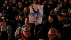 Ein Mann hält ein Plakat mit dem Regionalvorsitzenden der AfD Thüringen Björn Höcke und den Worten „Nie wieder“ während einer Mahnwache  in Hanau. Foto: AFP/Odd Andersen
