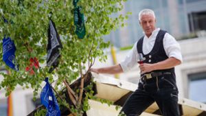 Tino Pietrobelli steht auf einem Laubendach und spricht den Richtspruch. Foto: Lichtgut//Christoph Schmidt