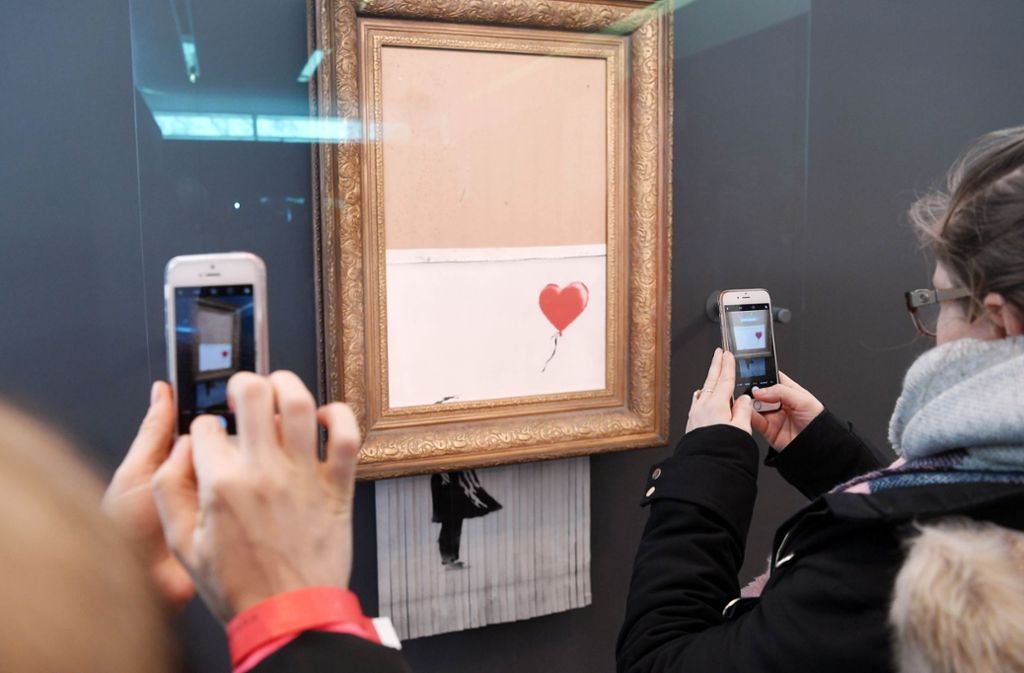 Besucher lichten das geschredderte Werk „Love is in the Bin“ in Baden-Baden mit ihren Smartphones ab.