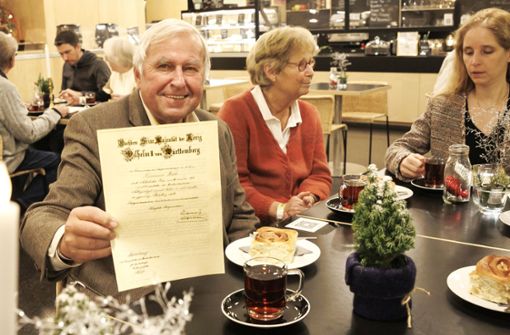 Rainer Welte zeigt die Urkunde, die sein Großvater 1916 vom König erhielt. Neben ihm seine Frau und rechts Jennifer Lauxmann-Stöhr. Foto: Lichtgut/Julian Rettig