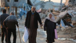 Menschen gehen an zerstörten Gebäuden im Flüchtlingslager Al-Maghazi im Zentrum des Gazastreifens vorbei. Das Bangen um eine Feuerpause vor Ramadan geht weiter. Foto: -/XinHua/dpa