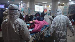 Ärzte mit Schutzanzügen bringen einen Patienten in ein Krankenhaus in Wuhan. Foto: AFP/Hector Retamal