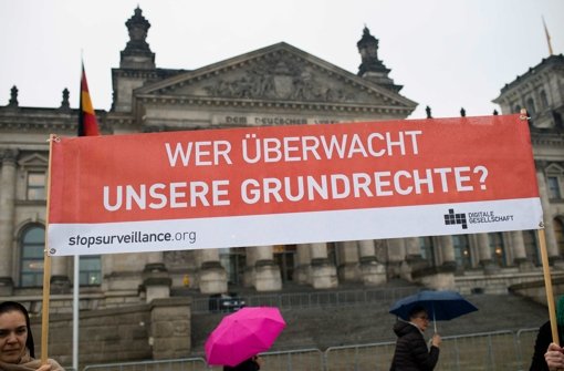 Aktivisten halten vor dem Reichstag in Berlin ein Transparent mit der Aufschrift «Wer überwacht unsere Grundrechte?», um gegen den Beschluss der Vorratsdatenspeicherung im Bundestag zu demonstrieren. Trotz Protesten von Opposition und Datenschützern stimmt der Bundestag dem neuen Gesetz zur Vorratsdatenspeicherung zu. Foto: dpa