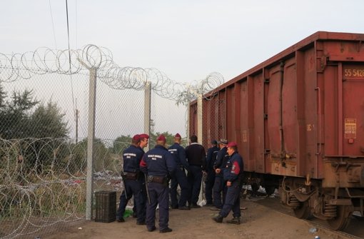 Polizisten sichern am Dienstag bei Röszke den Eisenbahnwaggon, mit dem am Vorabend das letzte Loch im ungarischen Zaun an der Grenze zu Serbien geschlossen worden war. Foto: dpa