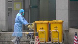 Ein Mitarbeiter eines Krankenhauses in der chinesischen Metropole Wuhan entsorgt Container mit Sondermüll. Foto: AP/Dake Kang