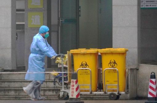 Ein Mitarbeiter eines Krankenhauses in der chinesischen Metropole Wuhan entsorgt Container mit Sondermüll. Foto: AP/Dake Kang