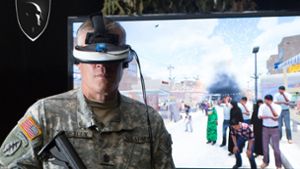 Ein Soldat setzt eine digitale Brille auf. Damit bekommt er die Virtuelle Realität des Kriegseinsatzes zu sehen, wie sie der Bildschirm hinter ihm zeigt. Foto: University of Southern California