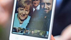 Rodin Saouan, Flüchtling aus Syrien, zeigt   auf seinem Smartphone ein Selfie-Foto, das er  zusammen mit Angela Merkel gemacht hat. Foto: dpa
