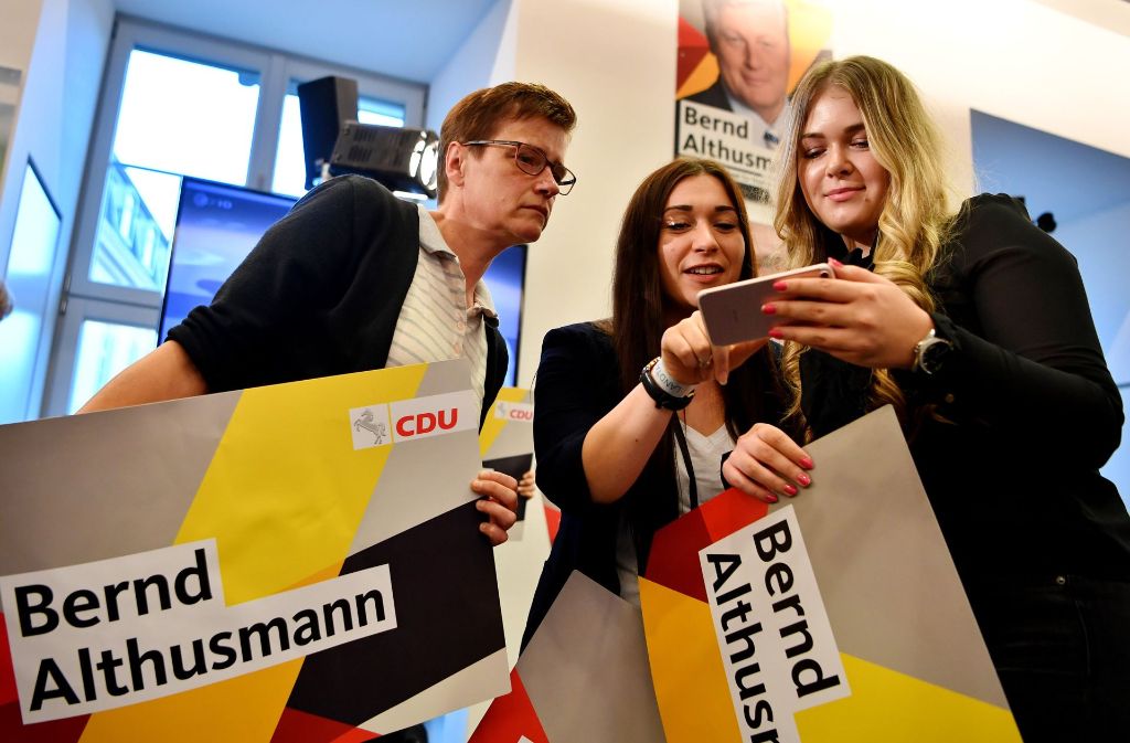 Unterstützer von Bernd Althusmann (CDU) schauten sich auf einem Smartphone die ersten Hochrechnungen der Landtagswahl an.