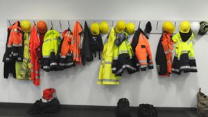 Symbolbild: Jacken und Helme von Hafenarbeiter hängen an einer Garderobe in einer deutschen Arbeiterkantine. Foto: dpa