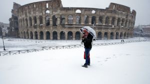 Ein Mann steht vor dem Kolosseum im Schnee. Ein Kältetief mit Schnee, Regen und starkem Wind hat Italien erreicht. Foto: AP