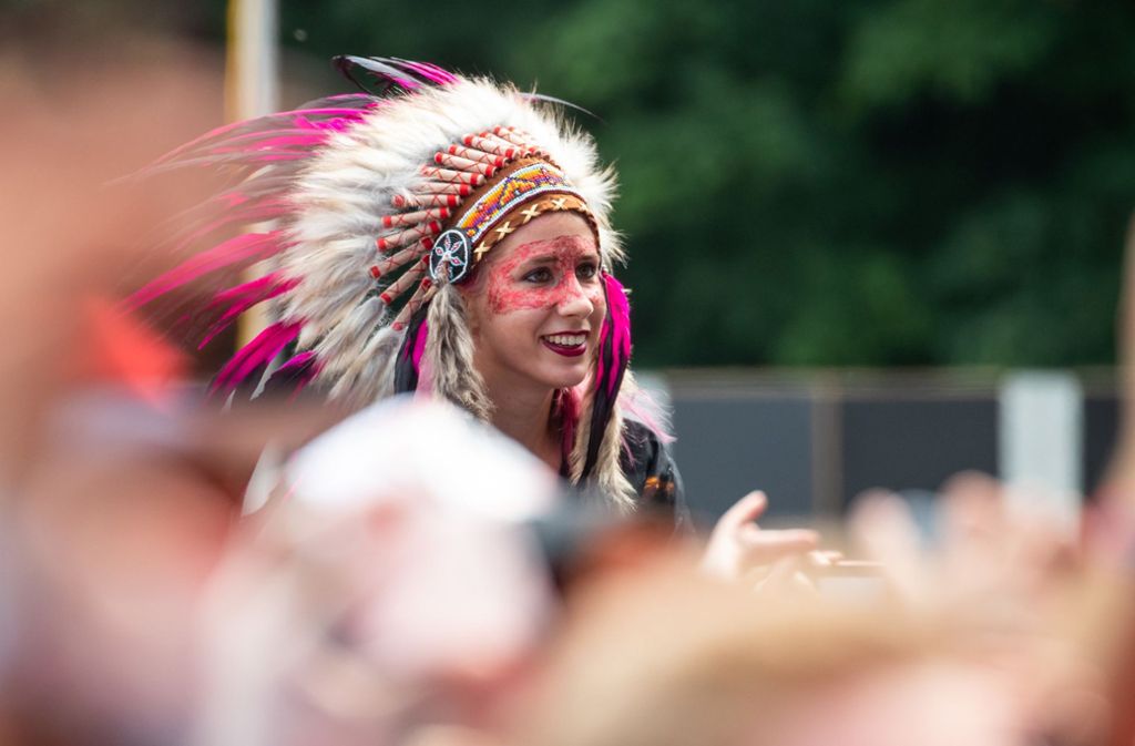 Eine Besucherin des Open-Air-Festivals „Rock im Park“ verfolgt in Indianerschmuck den Auftritt einer Band.