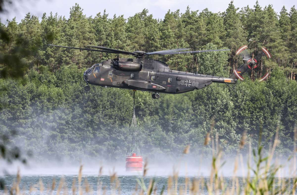 Ein Bundeswehrhubschrauber vom Typ Sikorsky CH-53 holt Löschwasser zur Waldbrandbekämpfung aus dem Kiebitzer Baggerteich nahe dem brandenburgischen Falkenberg. Foto: dpa/Jan Woitas