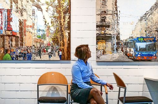 Die Kuratorin Elena Hocke sitzt zwischen zwei Stadtansichten der Ehninger Malerin Karin Allmendinger. Foto: Simon Granville