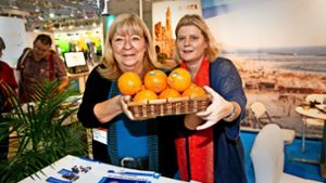Die von Renate Wikarski (links) und Henriette Pansold auf der CMT  angebotenen Früchte sehen aus wie Orangen. In Wahrheit sind  es   Minneolas, die vom sonnigen  Israel  aus den Weg über die raue Alb in die Stuttgarter Messehallen gefunden haben. Foto: Horst Rudel
