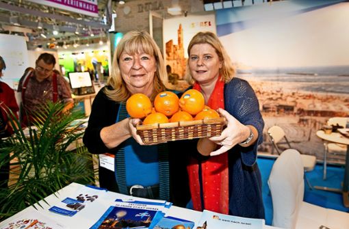 Die von Renate Wikarski (links) und Henriette Pansold auf der CMT  angebotenen Früchte sehen aus wie Orangen. In Wahrheit sind  es   Minneolas, die vom sonnigen  Israel  aus den Weg über die raue Alb in die Stuttgarter Messehallen gefunden haben. Foto: Horst Rudel