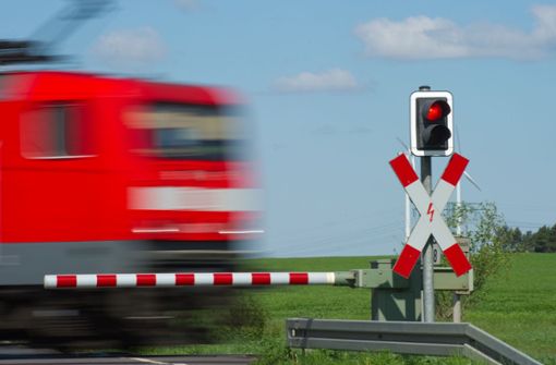 Halt! Ein Zug fährt bei  Jacobsdorf in Brandenburg an einem geschlossenem Bahnübergang mit Andreaskreuz und rotem Lichtsignal  vorbei. Foto: dpa/Patrick Pleul