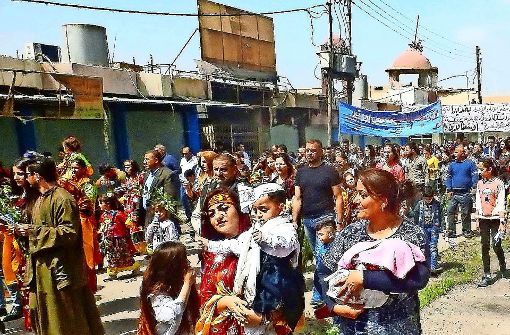 Ständige Angst vor Attentätern: Nach einem der seltenen Gottesdienste in Karakosch spazieren die Christen singend vorbei an ihren ausgeplünderten Geschäften und ausgebrannten Häusern. Foto: Jürgen Becker