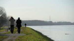 Spaziergänger laufen am 24.12.2012 in Karlsruhe auf einem Hochwasserdamm am Rhein. Foto: dpa