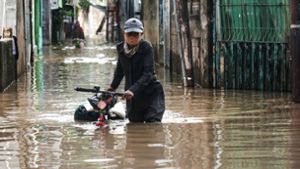 Eine Frau geht nach einem starken Regen in einem Wohngebiet der indonesischen Hauptstadt Jakarta durch das Flutwasser. Foto: Arya Manggala/XinHua/dpa Foto:  