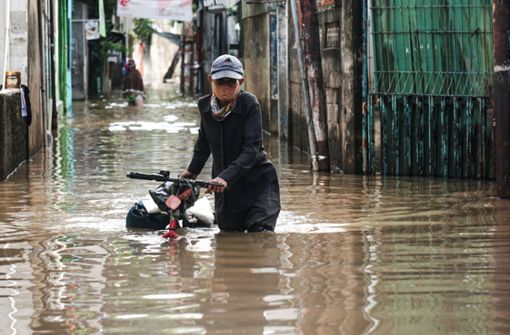Eine Frau geht nach einem starken Regen in einem Wohngebiet der indonesischen Hauptstadt Jakarta durch das Flutwasser. Foto: Arya Manggala/XinHua/dpa Foto:  