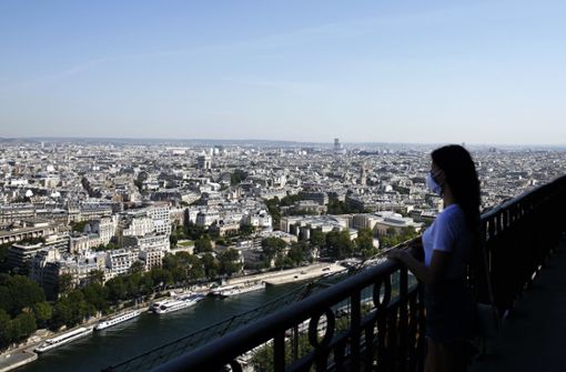 Eine Besucherin mit Nasen-Mundschutz genießt auf dem Eiffelturm die klare Aussicht auf Paris. Nach einer über dreimonatigen Zwangspause hat der Eiffelturm seine Pforten wieder geöffnet. Foto: dpa/Thibault Camus