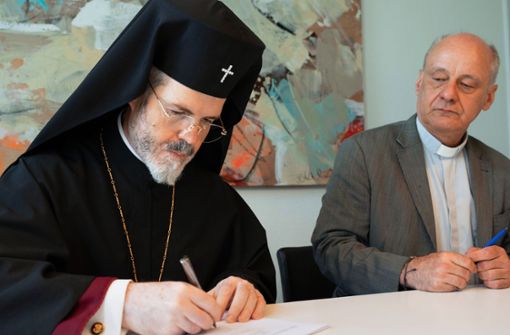 Der Metropolit Antonii unterschreibt den Kaufvertrag. Neben ihm Pfarrer Ludwig-Frank Mattes. Foto: Katholisches Stadtdekanat