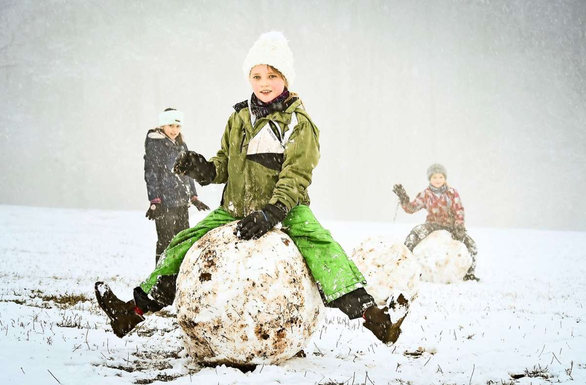 Kinder rollen große Schneekugeln auf der Egelseer Heide