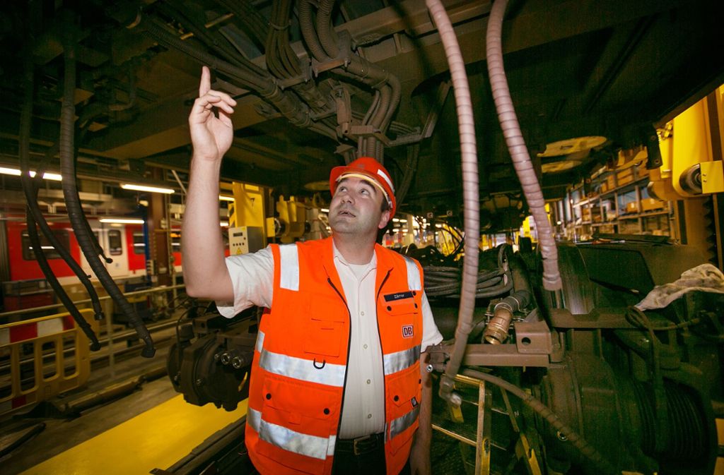 Werkstattleiter Michael Zörner zeigt auf den Unterbau einer hochgebockten S-Bahn im Betriebswerk Plochingen.