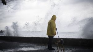 Ein Mann geht bei Rorschach (Schweiz) am Bodensee mit seinem Hund spazieren, während Sturm Burglind die Wellen gegen die Promenade treibt. Foto: dpa