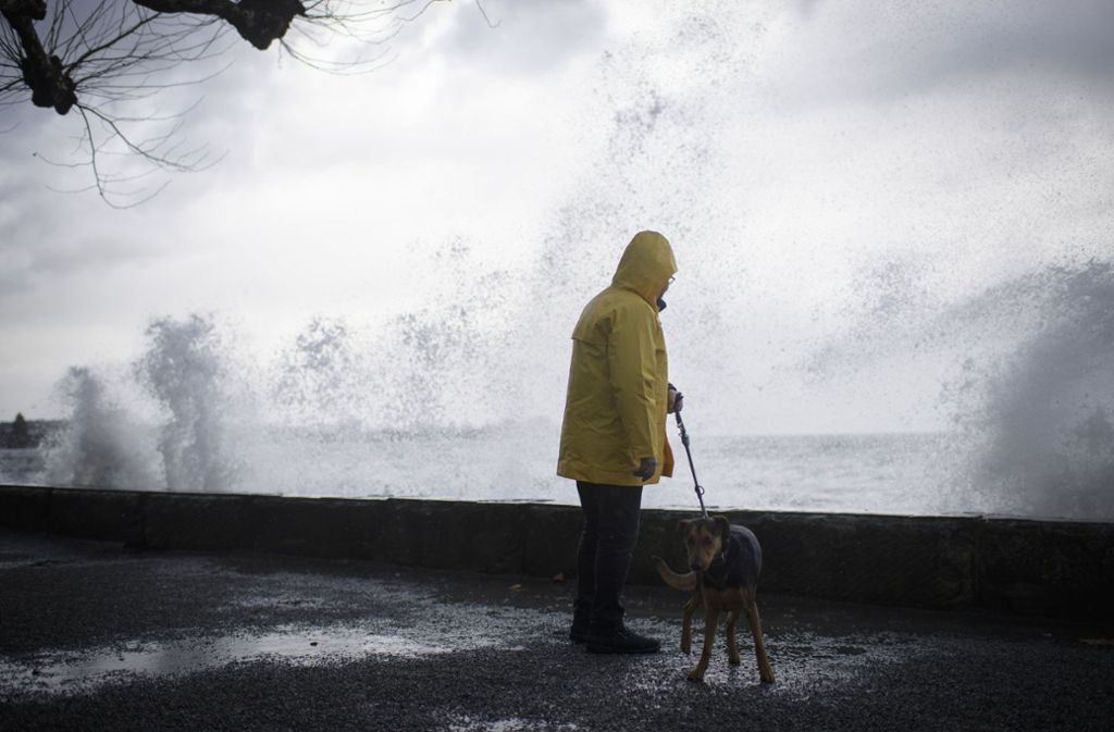Ein Mann geht bei Rorschach (Schweiz) am Bodensee mit seinem Hund spazieren, während Sturm Burglind die Wellen gegen die Promenade treibt.