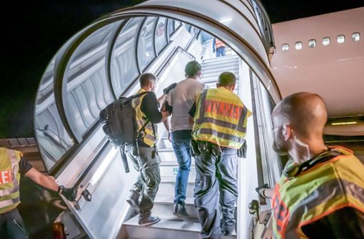 Polizeibeamte begleiten einen Migranten in Leipzig in ein Charterflugzeug. Foto: dpa/Michael Kappeler