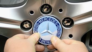 Ein Mitarbeiter befestigt   ein  Mercedes-Emblem an einem Rad Foto: dpa