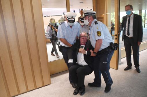 Der parteilose Landtagsabgeordnete Heinrich Fiechtner wurde von der Polizei aus dem Landtag getragen. Foto: dpa/Marijan Murat