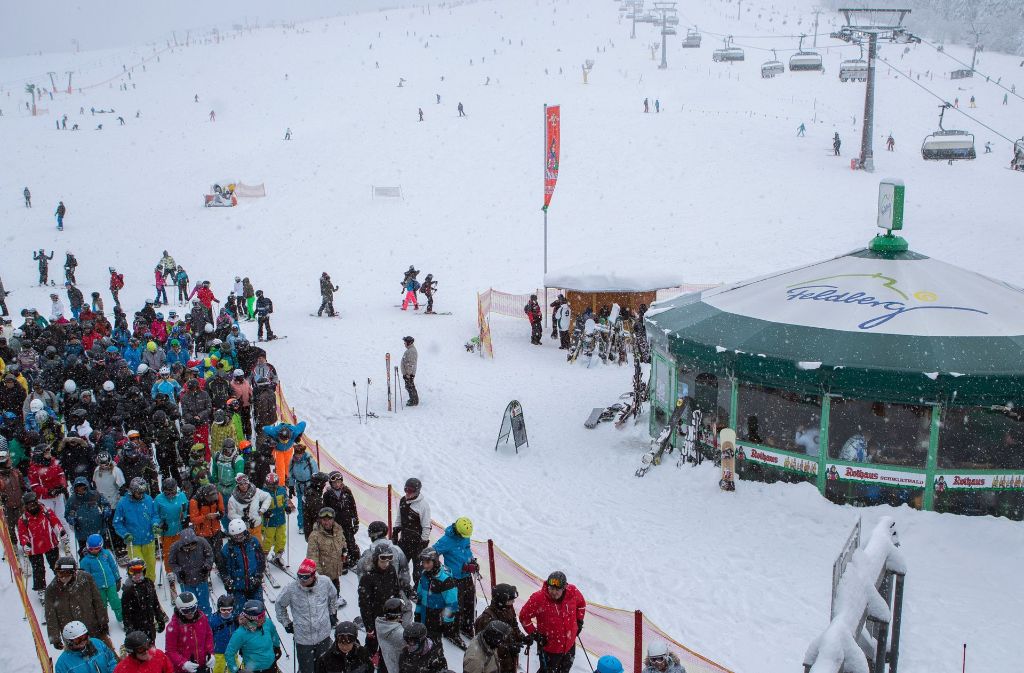 Zahlreiche Ski- und Snowboardfahrer stehen am Skilift auf dem höchsten Berg des Schwarzwaldes, dem Feldberg, an.