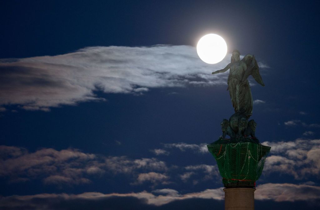 Der Mond leuchtet hinter der Statue der römischen Göttin Concordia, die auf der Jubiläumssäule über dem Stuttgarter Schlossplatz thront. Foto: dpa