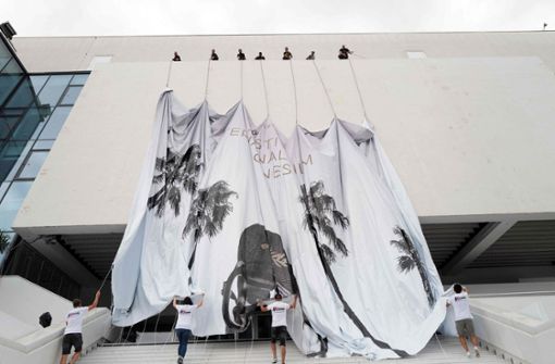 Mitarbeiter bringen ein riesiges Banner  am Festival- und Kongresspalast (Palais des Festivals et des Congres) in Cannes an. Die Filmfestspiele  beginnen am Abend des  6.  Juli. Foto: dpa/Valery Hache