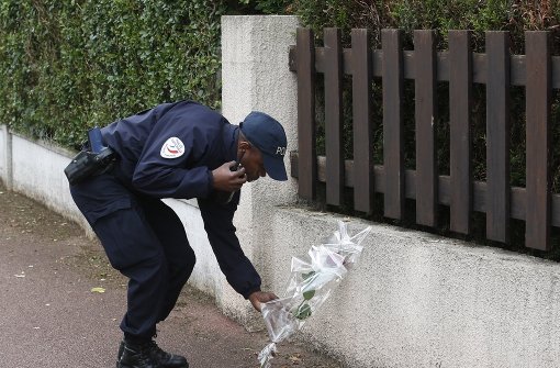 Ein Polizist legt Blumen nieder, nachdem ein mutmaßlicher Islamist zwei Polizisten nahe Paris ermordet hat. Foto: AP