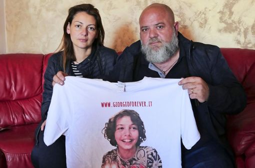 Carla Lucarelli und Angelo Di Ponzio  trauern um ihren  Sohn Giorgio, der an Krebs starb und dessen Gesicht sie auf T-Shirts haben drucken lassen. Foto: Almut Siefert