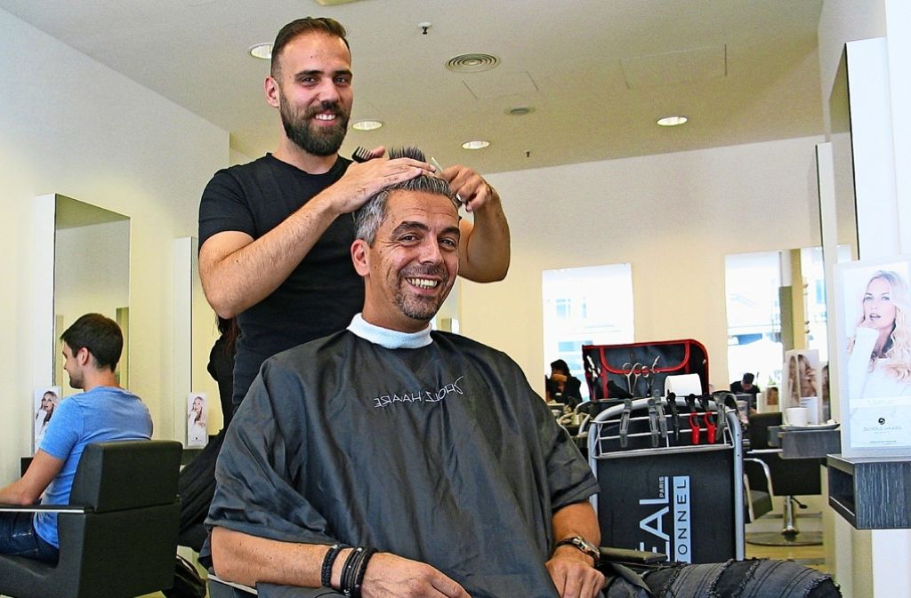 Der junge Syrer Maan Hilala schneidet dem Friseurmeister Vassili Keramaras die Haare.