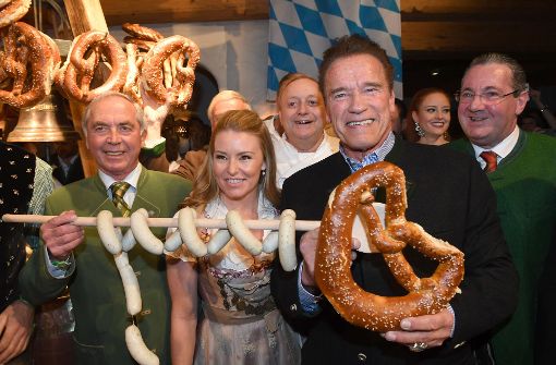 Arnold Schwarzenegger (rechts) freut sich gemeinsam mit Skifahrer Karl Schranz  und Heather Milligan über Riesenbrezel und Weißwürste. Foto: dpa