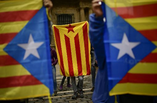 Menschen in Spanien halten am 1. Oktober die Flagge Kataloniens hoch. Foto: AP