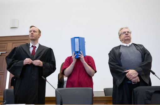 Der Angeklagte verbirgt sein Gesicht hinter einem Aktenordner. Foto: dpa/Boris Roessler