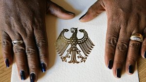 Eine Schwarzafrikanerin legt ihre Hände  auf eine Einbürgerungsurkunde Foto: dpa
