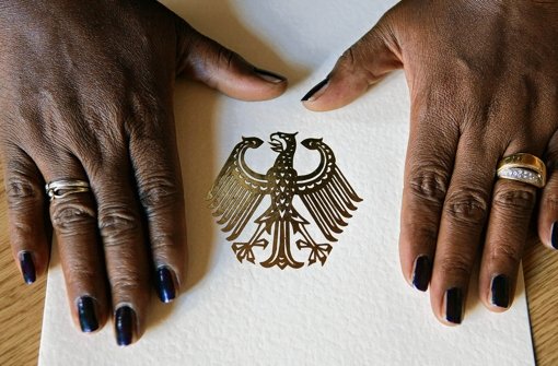 Eine Schwarzafrikanerin legt ihre Hände  auf eine Einbürgerungsurkunde Foto: dpa
